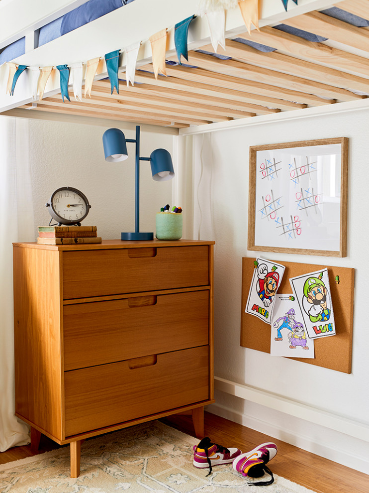 Cette image montre une petite chambre d'enfant de 4 à 10 ans avec un mur blanc, un sol en bois brun et un sol marron.