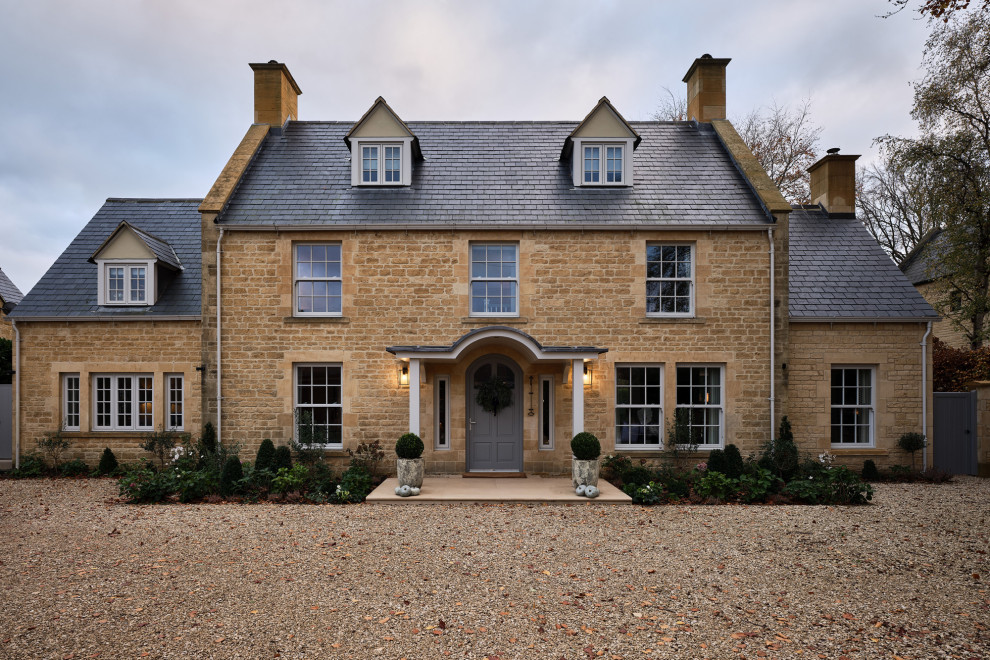 Стильный дизайн: трехэтажный частный загородный дом среднего размера в классическом стиле с облицовкой из камня, черепичной крышей и синей крышей - последний тренд