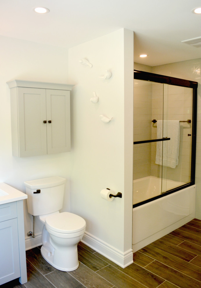 Пример оригинального дизайна: маленькая ванная комната со стиральной машиной в стиле рустика с фасадами в стиле шейкер, серыми фасадами, ванной в нише, душем над ванной, раздельным унитазом, серой плиткой, керамической плиткой, серыми стенами, полом из керамической плитки, врезной раковиной, столешницей из искусственного кварца, коричневым полом, душем с раздвижными дверями, белой столешницей и тумбой под одну раковину для на участке и в саду
