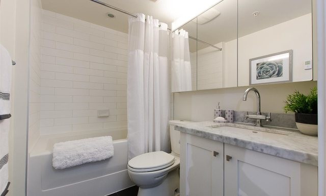 Small contemporary 3/4 bathroom in Vancouver with shaker cabinets, white cabinets, an alcove tub, a shower/bathtub combo, a two-piece toilet, gray tile, white tile, white walls, dark hardwood floors, an undermount sink and engineered quartz benchtops.