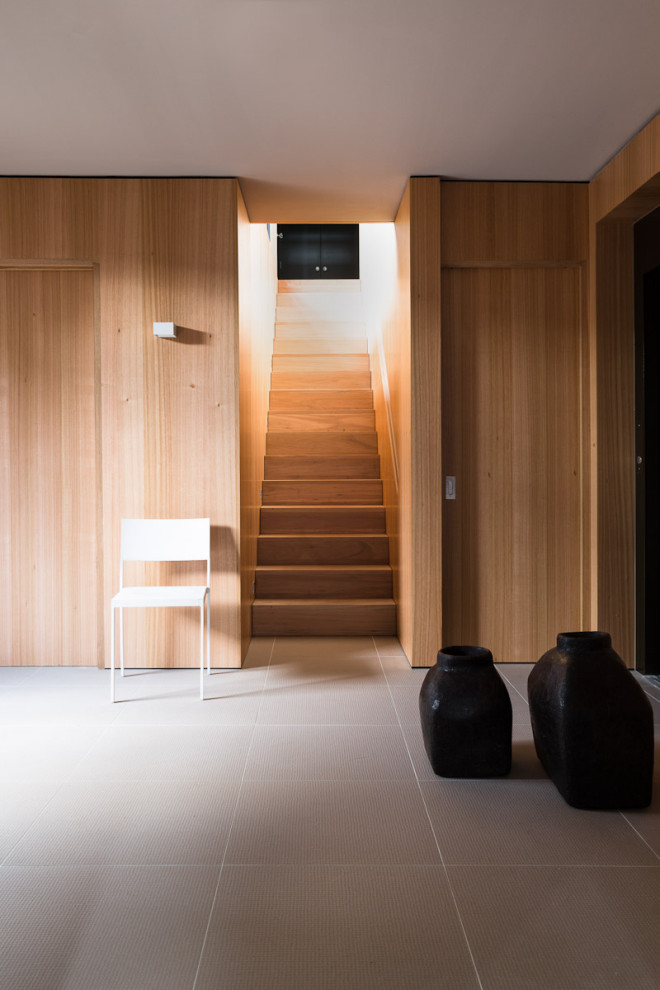 Photo of a large modern vestibule in Other with brown walls, porcelain floors, a single front door, a glass front door and grey floor.