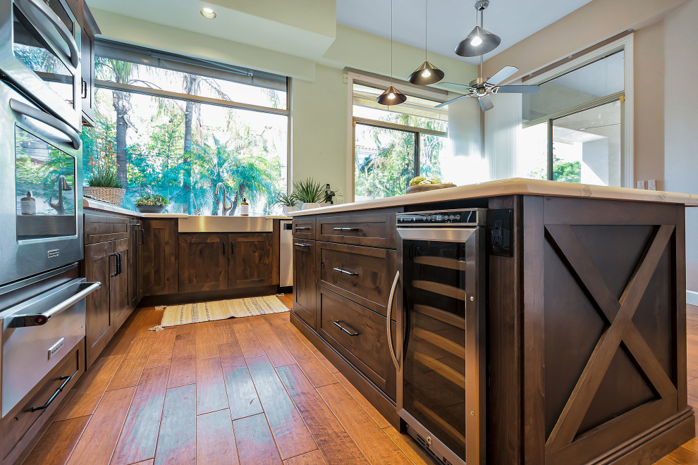 Large transitional u-shaped open concept kitchen photo in Phoenix with a farmhouse sink, shaker cabinets, dark wood cabinets, quartz countertops, white backsplash, quartz backsplash, stainless steel appliances, an island and white countertops