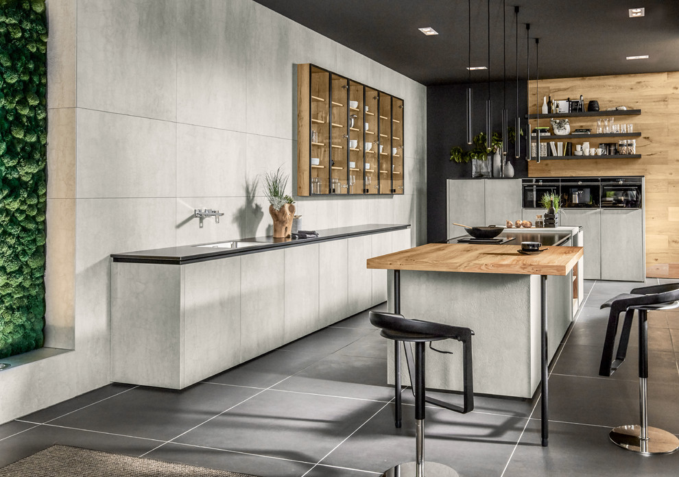 Design ideas for a large country galley eat-in kitchen in Other with a drop-in sink, ceramic splashback, black appliances, concrete floors, multiple islands, black floor, black benchtop, flat-panel cabinets, grey cabinets and grey splashback.