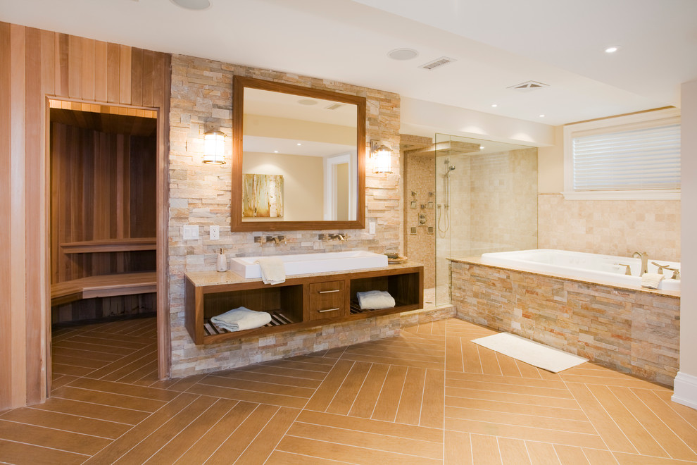 Photo of a large arts and crafts bathroom in Toronto with open cabinets, medium wood cabinets, a drop-in tub, an alcove shower, beige tile, brown tile, stone tile, porcelain floors, with a sauna, a vessel sink, granite benchtops, brown floor and a hinged shower door.