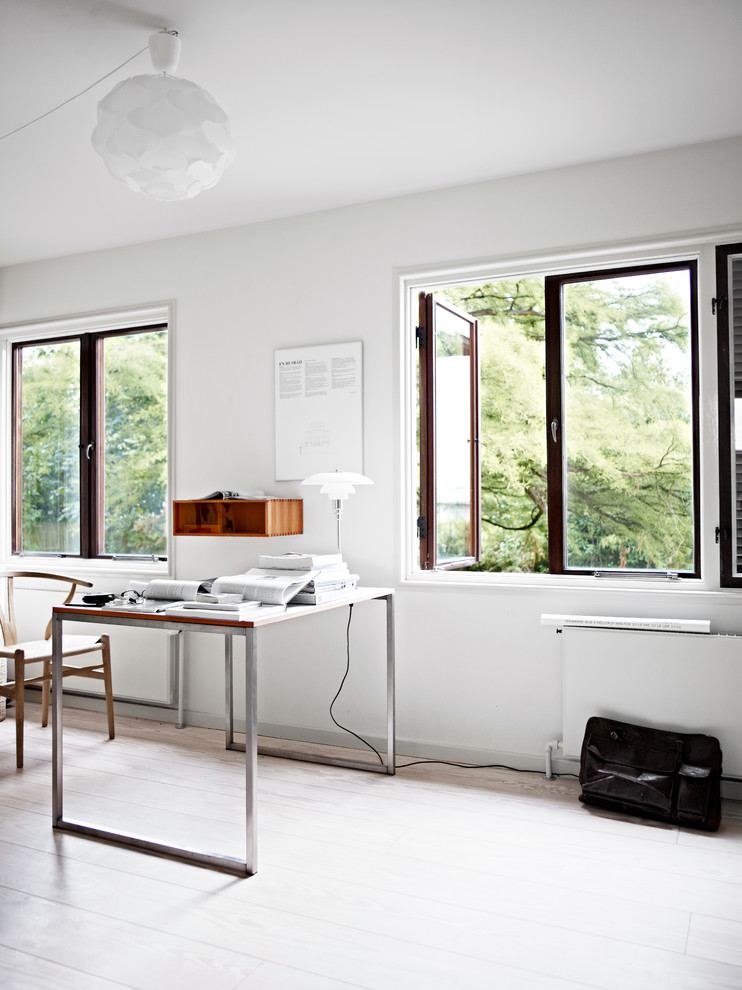 Photo of a scandinavian home office in Copenhagen with white walls, light hardwood floors, a freestanding desk and beige floor.