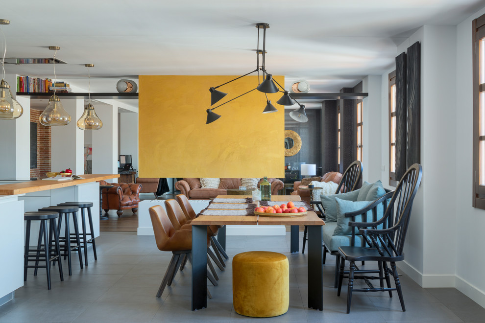 Inspiration for an eclectic open plan dining in Malaga with white walls, concrete floors, a ribbon fireplace, a plaster fireplace surround and grey floor.