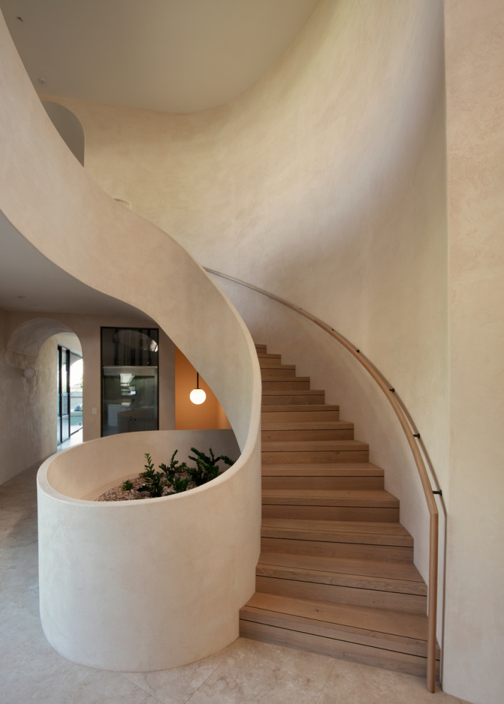 Foto de escalera curva mediterránea extra grande con escalones de madera, contrahuellas de madera y barandilla de madera