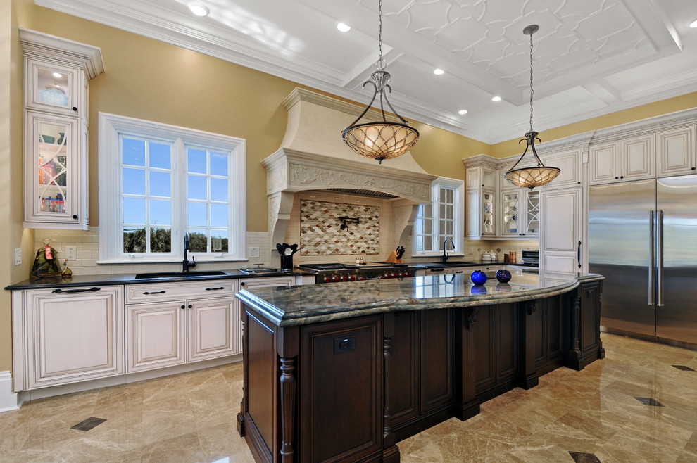 Photo of an expansive traditional u-shaped eat-in kitchen in Tampa with an undermount sink, raised-panel cabinets, white cabinets, quartz benchtops, white splashback, subway tile splashback, stainless steel appliances, marble floors, with island and beige floor.