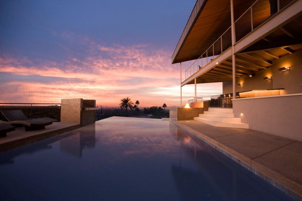 Large backyard concrete and custom-shaped infinity pool fountain photo in Phoenix