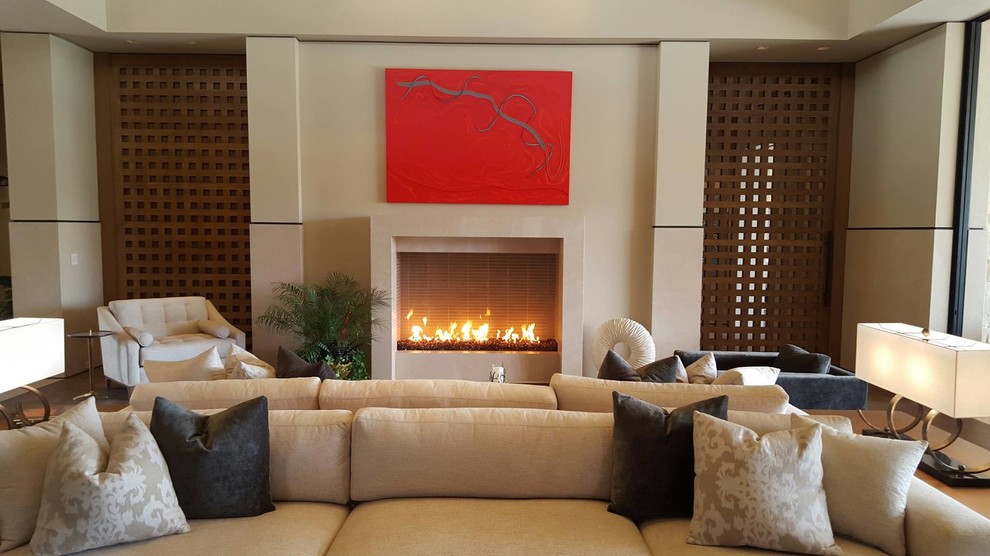 This is an example of a mid-sized asian formal enclosed living room in San Diego with beige walls, light hardwood floors, a standard fireplace, a plaster fireplace surround, no tv and beige floor.