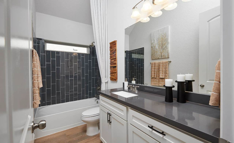 Inredning av ett modernt grå grått badrum, med luckor med infälld panel, vita skåp, ett badkar i en alkov, en dusch/badkar-kombination, laminatgolv, ett undermonterad handfat, brunt golv, dusch med duschdraperi och grå kakel