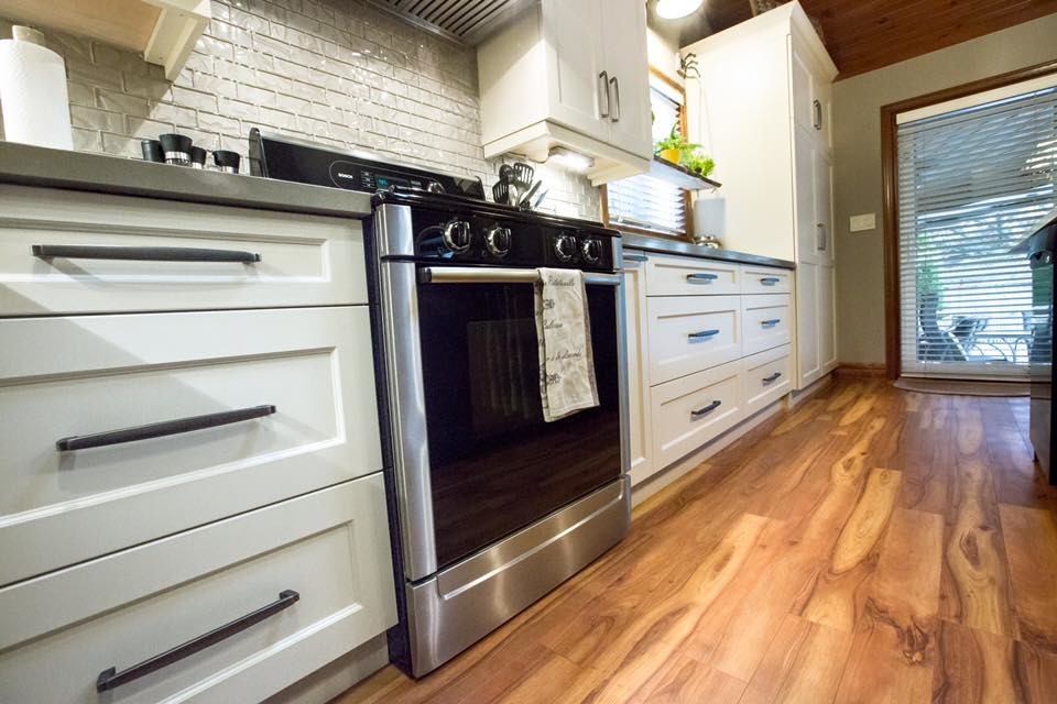 Inspiration for a mid-sized transitional l-shaped medium tone wood floor and brown floor eat-in kitchen remodel with an undermount sink, shaker cabinets, white cabinets, quartzite countertops, white backsplash, subway tile backsplash, paneled appliances and an island