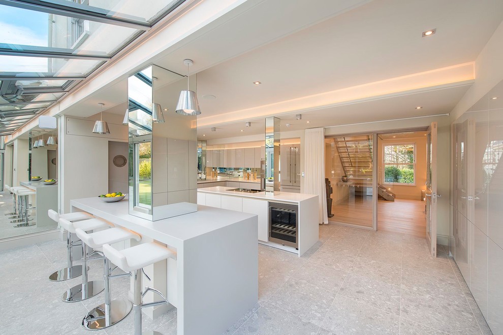 Inspiration for a large contemporary l-shaped kitchen in Hertfordshire with an integrated sink, flat-panel cabinets, grey cabinets, solid surface benchtops, metallic splashback, mirror splashback, stainless steel appliances, porcelain floors, multiple islands, white benchtop and grey floor.