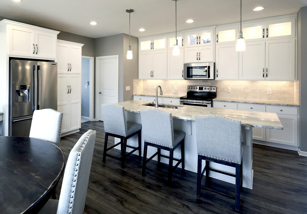Eat-in kitchen - transitional l-shaped gray floor eat-in kitchen idea with an undermount sink, glass-front cabinets, white cabinets, stainless steel appliances, an island, beige backsplash, stone tile backsplash and multicolored countertops