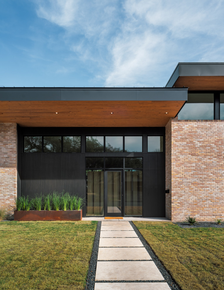 Aménagement d'une grande façade de maison rétro en brique et planches et couvre-joints à un étage avec un toit papillon, un toit en métal et un toit noir.
