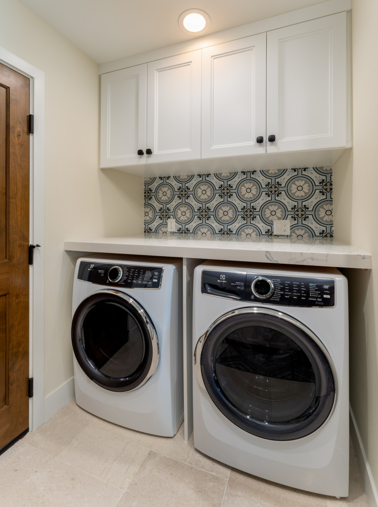 Inspiration for a mid-sized country galley dedicated laundry room in Orange County with an undermount sink, recessed-panel cabinets, white cabinets, quartz benchtops, multi-coloured splashback, cement tile splashback, white walls, limestone floors, a side-by-side washer and dryer, beige floor and white benchtop.