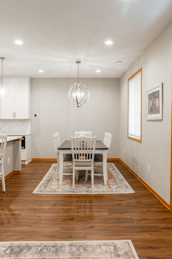Photo of a large transitional dining room in Minneapolis with grey walls, vinyl floors, a corner fireplace and brown floor.