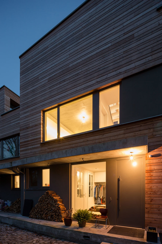 Photo of a large contemporary two-storey brown duplex exterior in Berlin with wood siding, a flat roof, a green roof and clapboard siding.