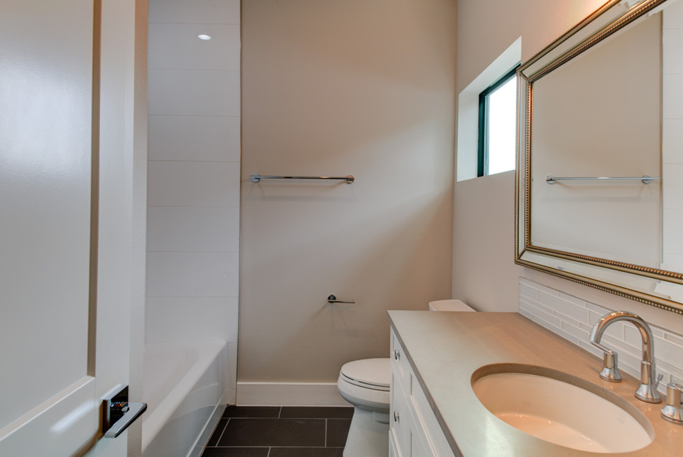 Design ideas for a mid-sized contemporary bathroom in Austin with shaker cabinets, white cabinets, a one-piece toilet, porcelain tile, grey walls, an alcove tub, a shower/bathtub combo, white tile, porcelain floors, an undermount sink, grey floor, a shower curtain and solid surface benchtops.