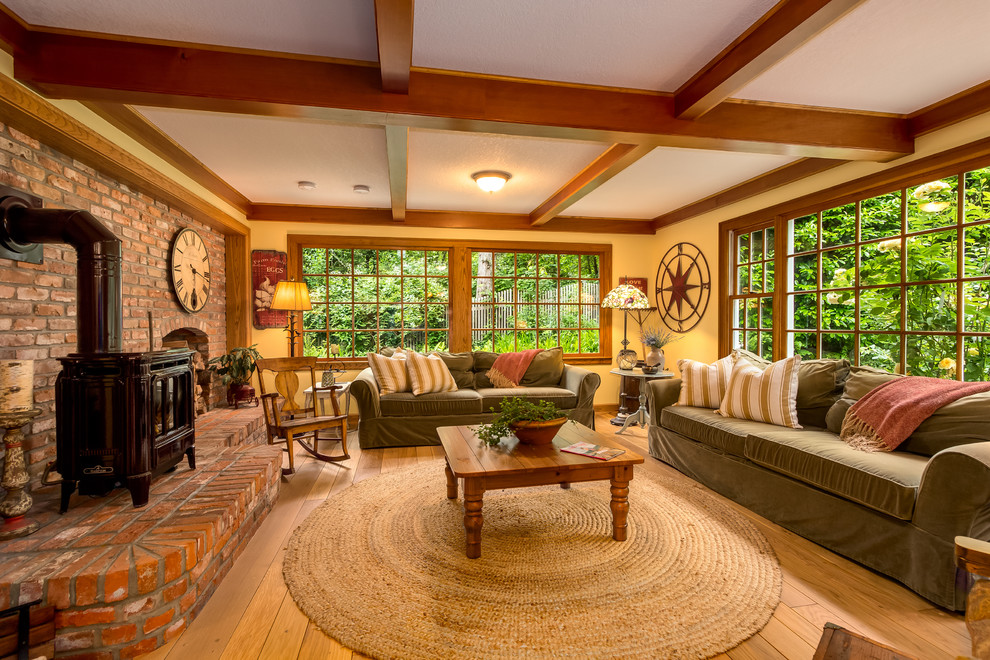 Large country enclosed family room in Seattle with yellow walls, medium hardwood floors, a wood stove and a brick fireplace surround.