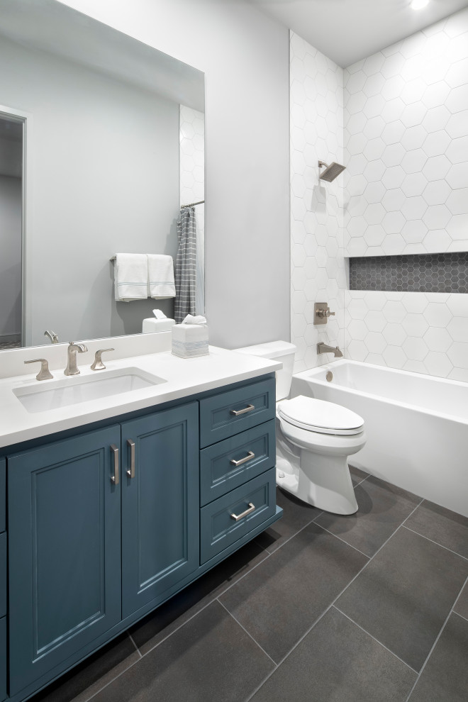 Mid-sized country kids bathroom in Austin with recessed-panel cabinets, blue cabinets, an alcove tub, an alcove shower, a two-piece toilet, white tile, ceramic tile, grey walls, ceramic floors, an undermount sink, engineered quartz benchtops, grey floor, a shower curtain, white benchtops, a niche, a single vanity and a built-in vanity.