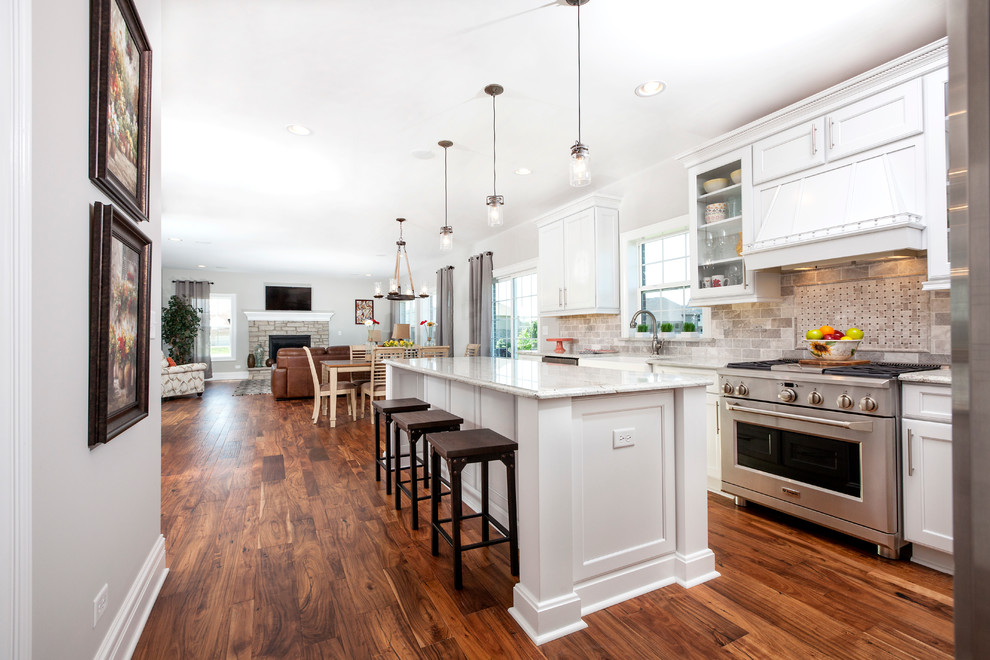 This is an example of a traditional l-shaped eat-in kitchen in Chicago with a farmhouse sink, recessed-panel cabinets, white cabinets, granite benchtops, grey splashback, stone tile splashback, stainless steel appliances, medium hardwood floors and with island.