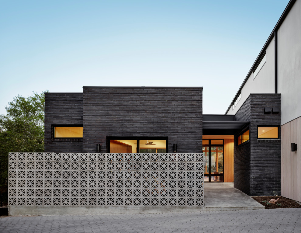Cette image montre une façade de maison multicolore vintage en brique à un étage avec un toit plat, un toit en métal et un toit noir.