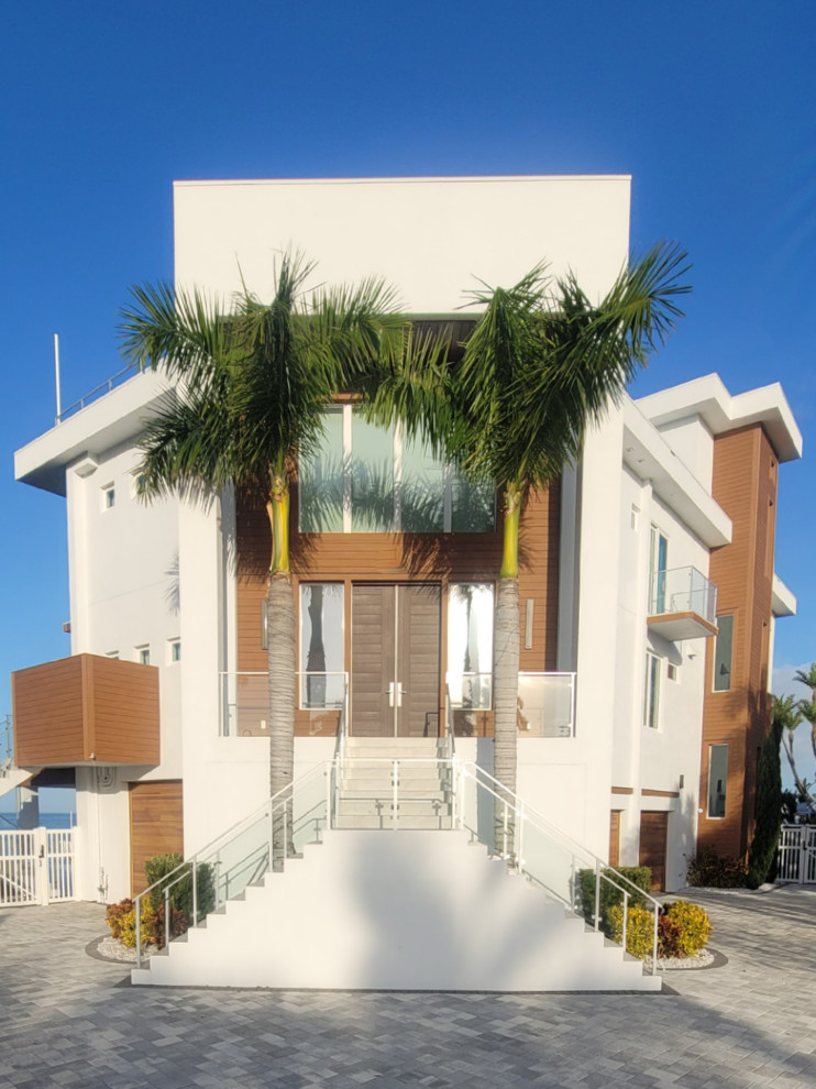 タンパにあるラグジュアリーな広いビーチスタイルのおしゃれな玄関ドア (白い壁、木目調のドア) の写真