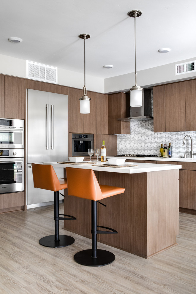 Photo of a contemporary l-shaped kitchen in San Diego with flat-panel cabinets, medium wood cabinets, white splashback, mosaic tile splashback, light hardwood floors, with island, beige floor and white benchtop.