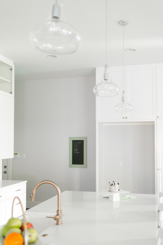 Example of a transitional single-wall open concept kitchen design in Houston with shaker cabinets, white cabinets, quartzite countertops, white backsplash, an island and white countertops
