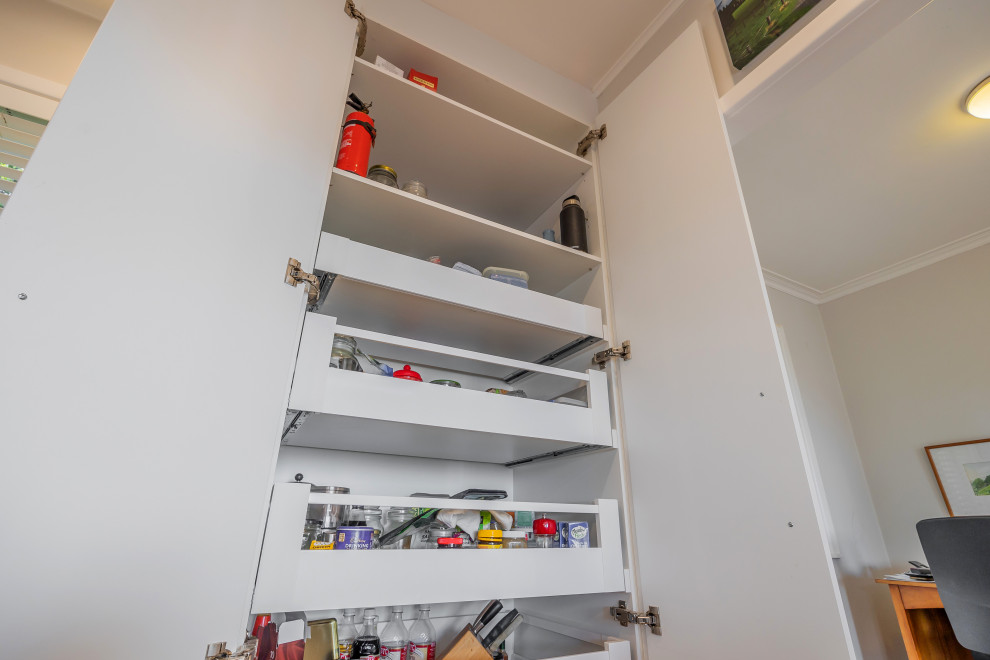 Small modern galley kitchen pantry in Auckland with an undermount sink, flat-panel cabinets, white cabinets, quartz benchtops, black splashback, ceramic splashback, stainless steel appliances, light hardwood floors, no island, brown floor and grey benchtop.