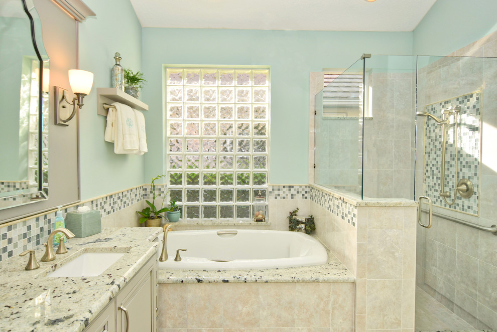 This is an example of a mid-sized traditional master bathroom in Other with a hot tub, an alcove shower, beige tile, porcelain tile, blue walls, an undermount sink, granite benchtops, porcelain floors, raised-panel cabinets, grey cabinets, beige floor and a hinged shower door.
