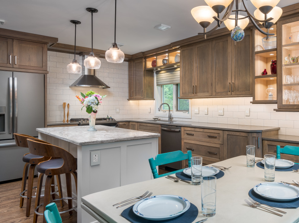 Eat-in kitchen - transitional l-shaped medium tone wood floor and brown floor eat-in kitchen idea in Minneapolis with an undermount sink, shaker cabinets, medium tone wood cabinets, white backsplash, subway tile backsplash, stainless steel appliances, an island and gray countertops