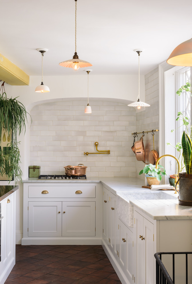 Design ideas for a large traditional eat-in kitchen in Other with a farmhouse sink, shaker cabinets, white cabinets, marble benchtops, white splashback, subway tile splashback, panelled appliances, terra-cotta floors, with island and brown floor.