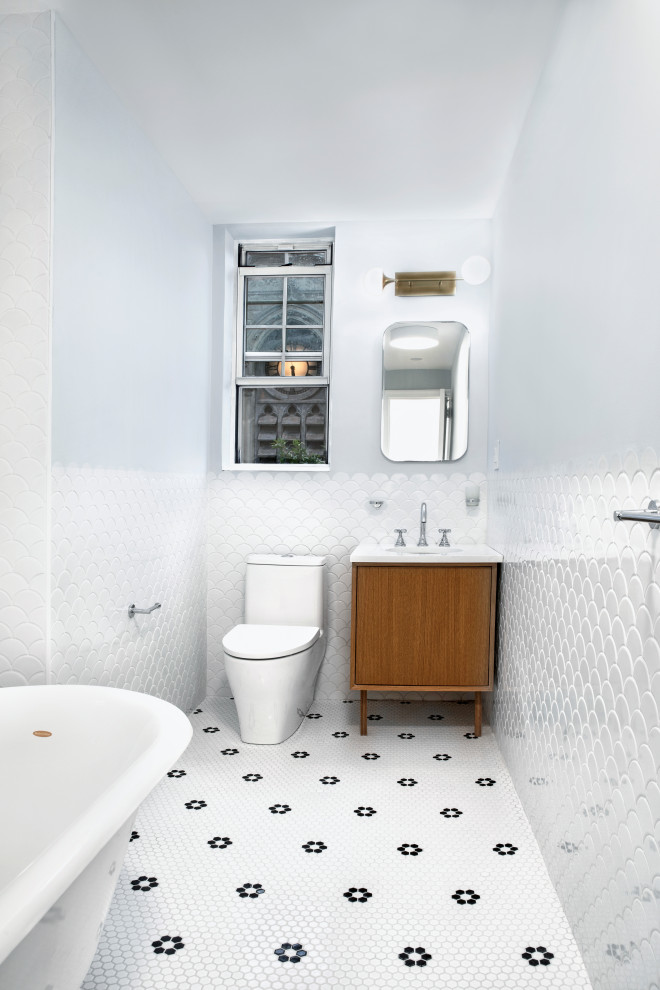 Photo of a mid-sized midcentury bathroom in New York with flat-panel cabinets, brown cabinets, a claw-foot tub, a one-piece toilet, white tile, ceramic tile, blue walls, ceramic floors, a console sink, marble benchtops, white floor, white benchtops, a single vanity and a freestanding vanity.