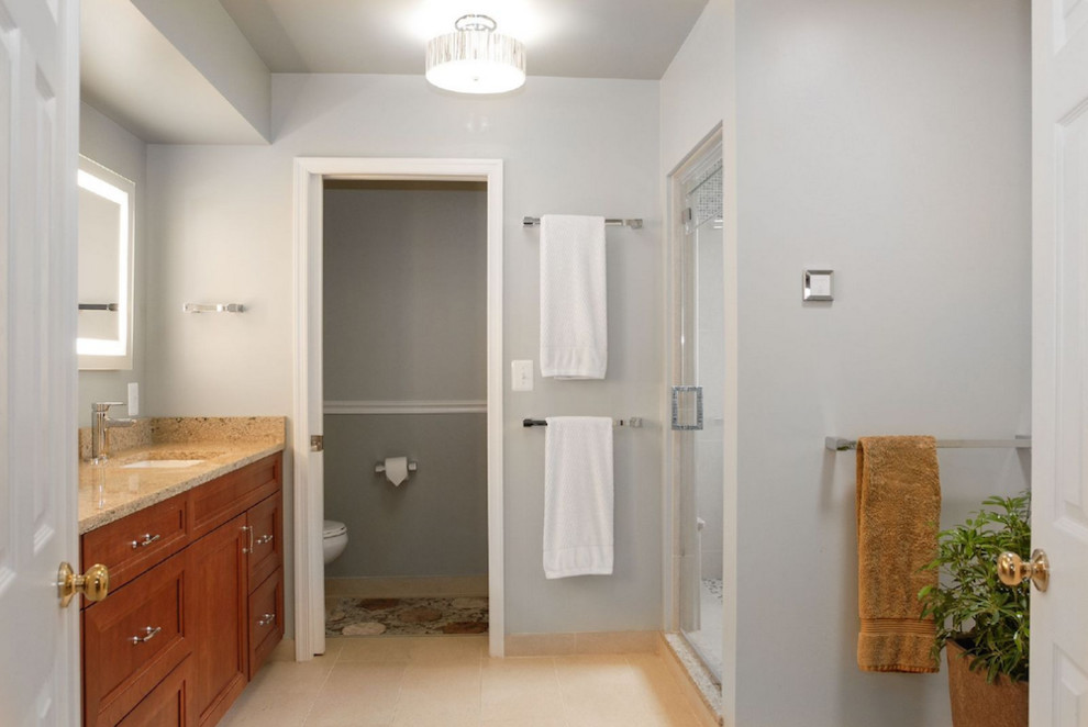 Design ideas for a large traditional master bathroom in Baltimore with recessed-panel cabinets, medium wood cabinets, a two-piece toilet, gray tile, grey walls, ceramic floors, solid surface benchtops, an alcove shower, ceramic tile and an undermount sink.