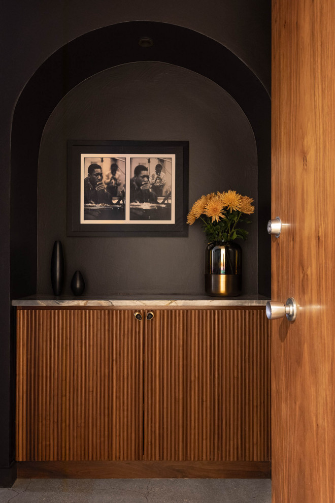 Cette photo montre un hall d'entrée tendance avec un mur noir, sol en béton ciré, une porte simple et une porte en bois brun.