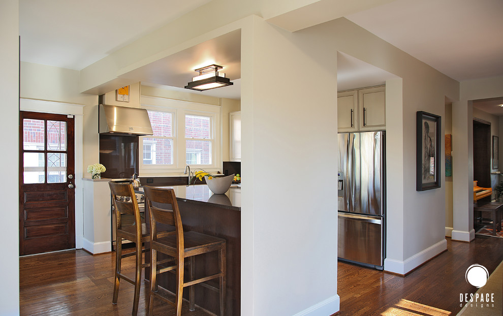 Example of a mid-sized transitional l-shaped medium tone wood floor eat-in kitchen design in DC Metro with a peninsula, an undermount sink, recessed-panel cabinets, white cabinets, brown backsplash and stainless steel appliances