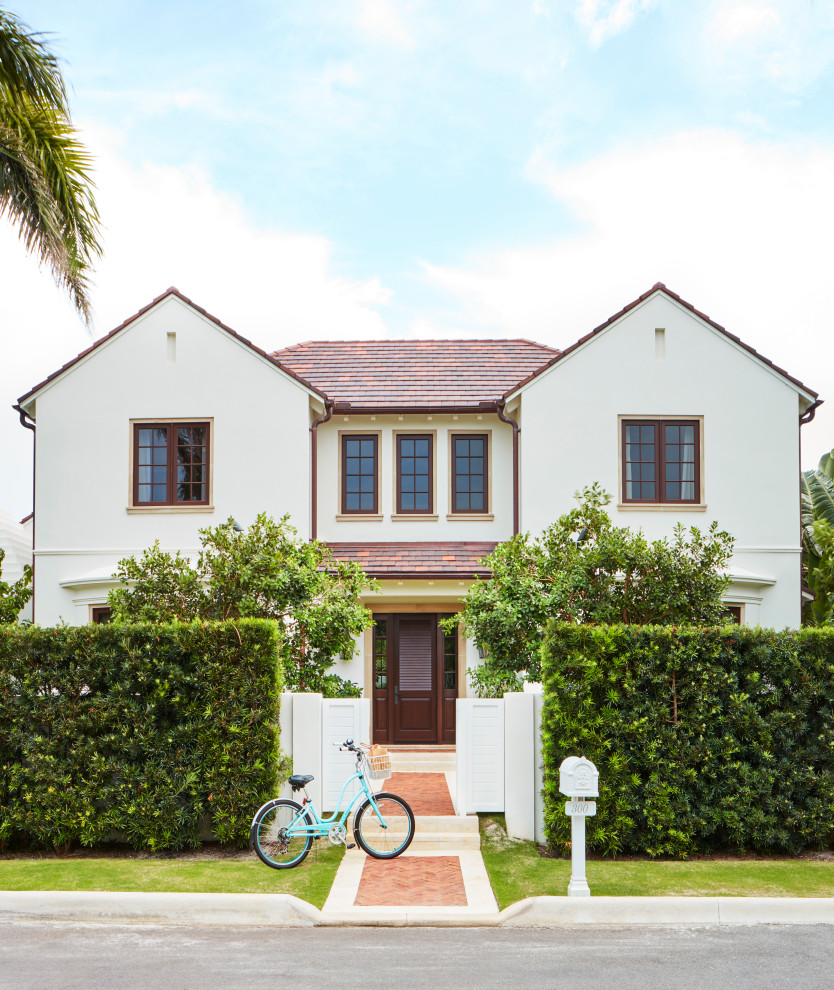 Photo of a mediterranean two-storey white house exterior in Miami with a gable roof, a tile roof and a red roof.