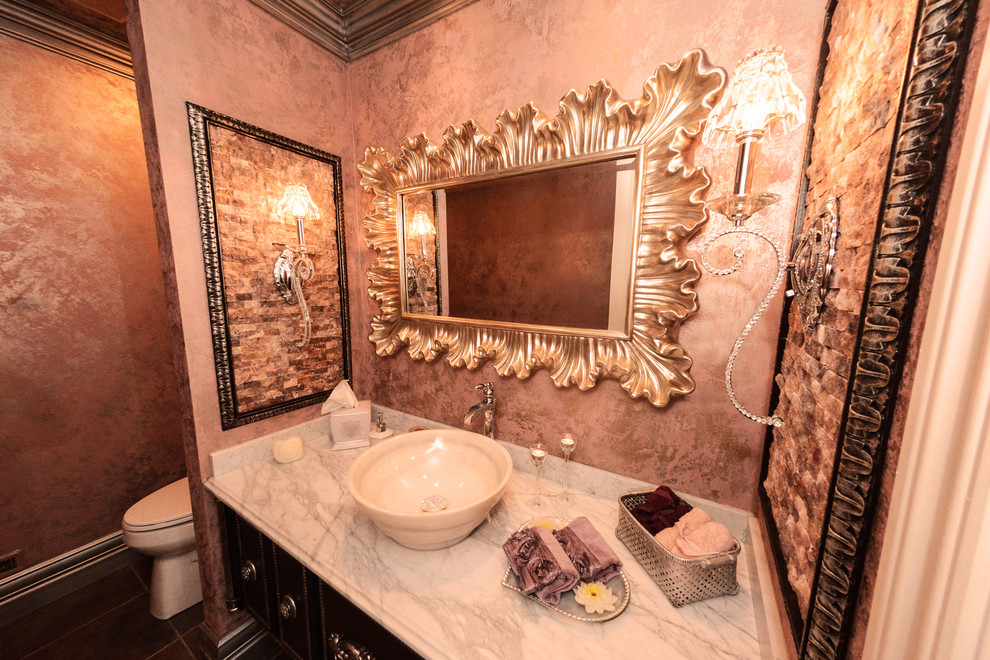 Photo of a traditional powder room in Detroit with a vessel sink, dark wood cabinets, marble benchtops, a one-piece toilet, multi-coloured tile, porcelain tile, pink walls and porcelain floors.