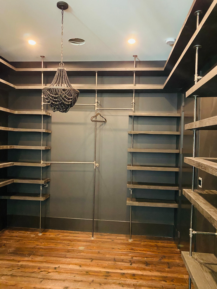 This is an example of a mid-sized industrial gender-neutral storage and wardrobe in Other with open cabinets, dark wood cabinets and medium hardwood floors.