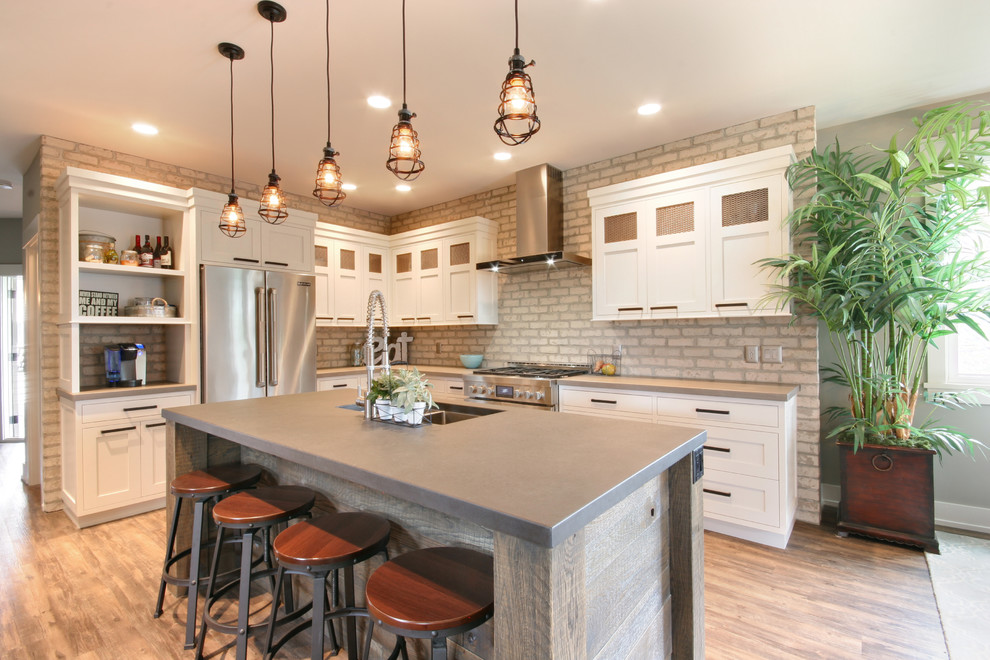 Mid-sized industrial l-shaped open plan kitchen in Grand Rapids with an undermount sink, recessed-panel cabinets, white cabinets, concrete benchtops, stainless steel appliances, vinyl floors and with island.