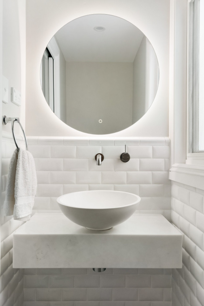 This is an example of a transitional powder room in Sydney with white cabinets, solid surface benchtops, white benchtops and a floating vanity.