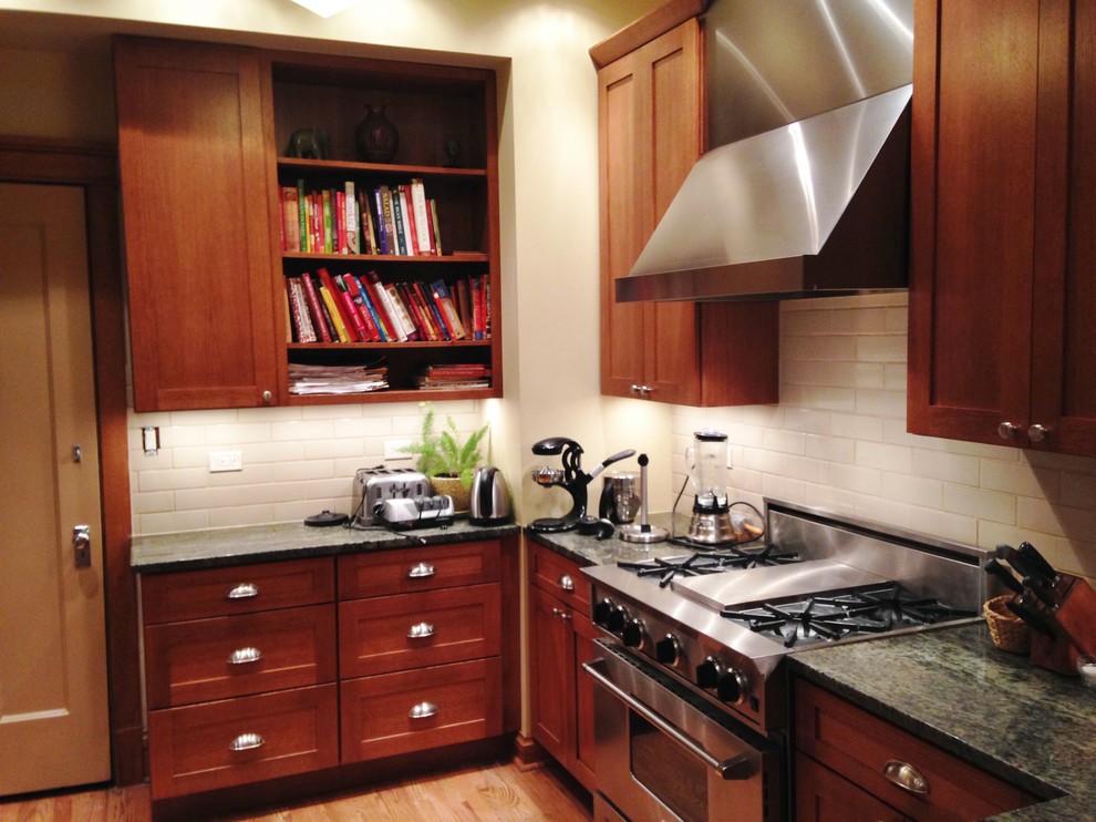 Example of a transitional galley eat-in kitchen design in Chicago with a farmhouse sink, shaker cabinets, medium tone wood cabinets, granite countertops, beige backsplash, subway tile backsplash and stainless steel appliances