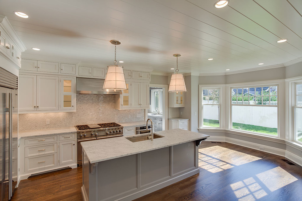 Inspiration for a mid-sized transitional l-shaped dark wood floor and brown floor eat-in kitchen remodel with an undermount sink, recessed-panel cabinets, white cabinets, white backsplash, stainless steel appliances, an island and marble countertops