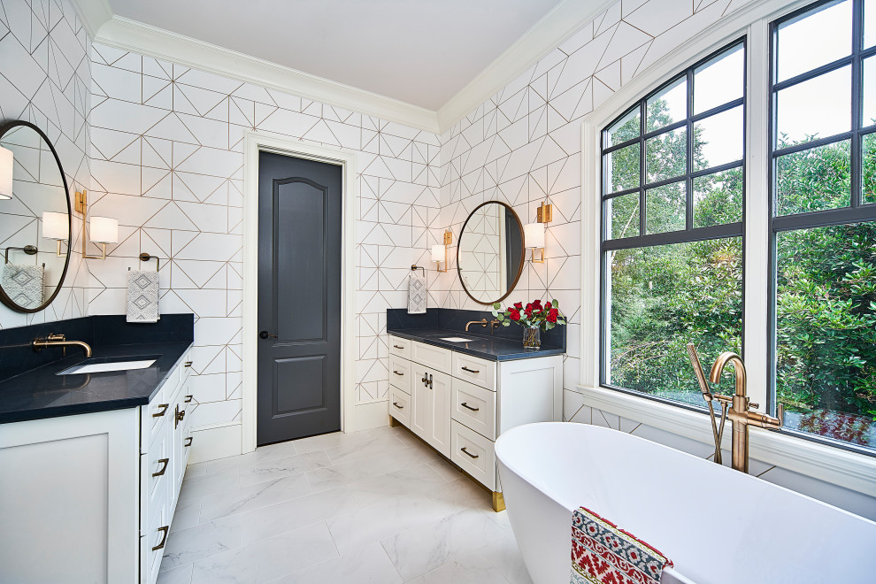 Photo of a mid-sized transitional master bathroom in Charlotte with shaker cabinets, white cabinets, a freestanding tub, an alcove shower, a two-piece toilet, white tile, porcelain tile, white walls, porcelain floors, an undermount sink, engineered quartz benchtops, white floor, a sliding shower screen and black benchtops.