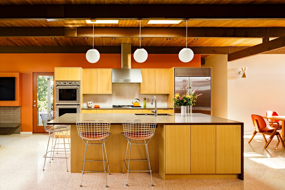 This is an example of a mid-sized midcentury galley open plan kitchen in Portland with an undermount sink, flat-panel cabinets, medium wood cabinets, quartz benchtops, white splashback, ceramic splashback, stainless steel appliances, terrazzo floors, with island and multi-coloured floor.