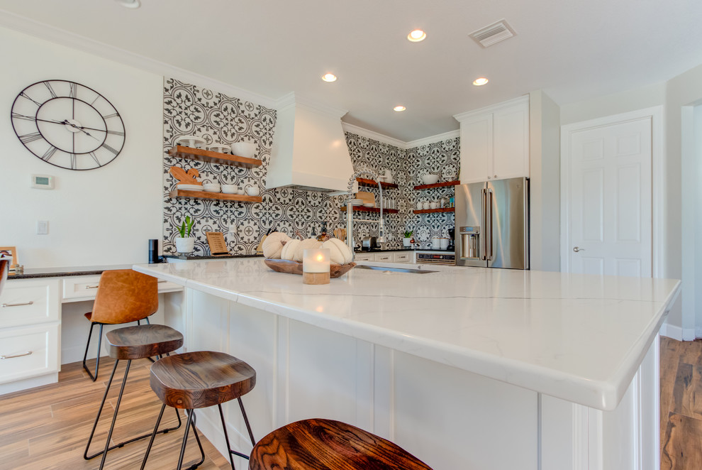 Large transitional l-shaped ceramic tile and brown floor eat-in kitchen photo with an undermount sink, shaker cabinets, white cabinets, quartz countertops, multicolored backsplash, ceramic backsplash, stainless steel appliances, an island and white countertops