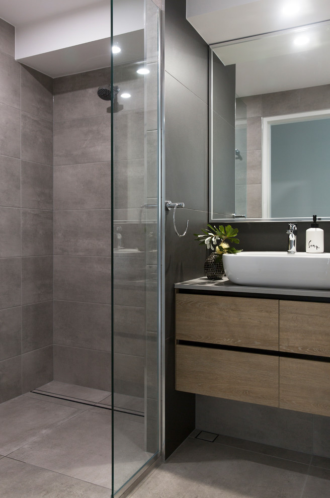 Inspiration for a small contemporary master bathroom in Sunshine Coast with flat-panel cabinets, light wood cabinets, a corner shower, a one-piece toilet, gray tile, porcelain tile, grey walls, porcelain floors, a vessel sink, engineered quartz benchtops, grey floor, a hinged shower door and grey benchtops.