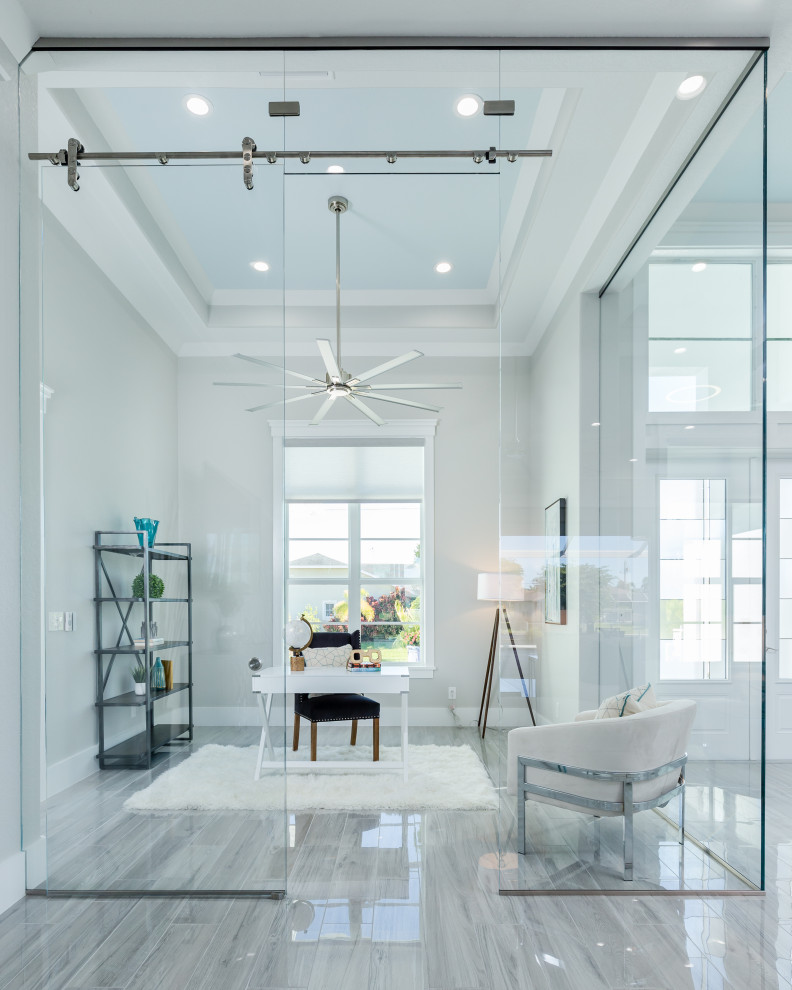 This is an example of a medium sized contemporary home office in Miami with grey walls, ceramic flooring, a freestanding desk, grey floors and a drop ceiling.